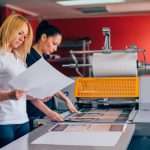 Dos jóvenes que trabajan en una imprenta. Prensa de impresión